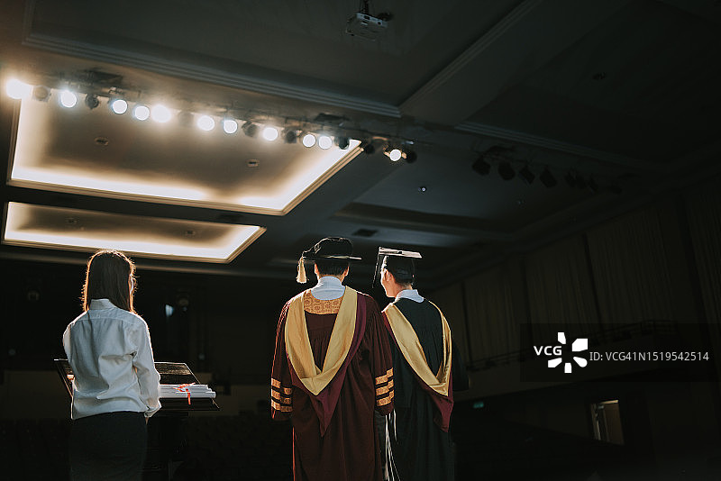 毕业典礼后视图：亚洲大学生与院长在台上合影图片素材