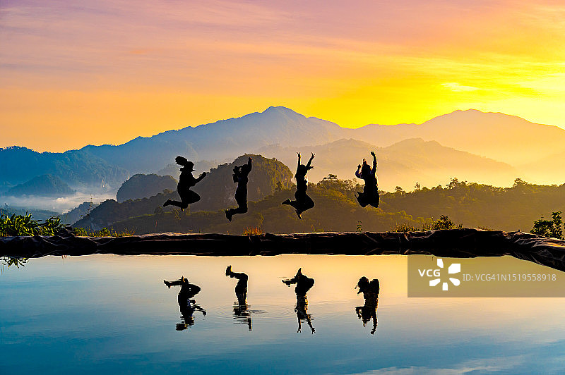 日落时分，快乐的女人在山间田野里跳跃着享受生活。一群快乐的徒步旅行者在山丘上跳跃，享受徒步旅行的假日和野外探险图片素材
