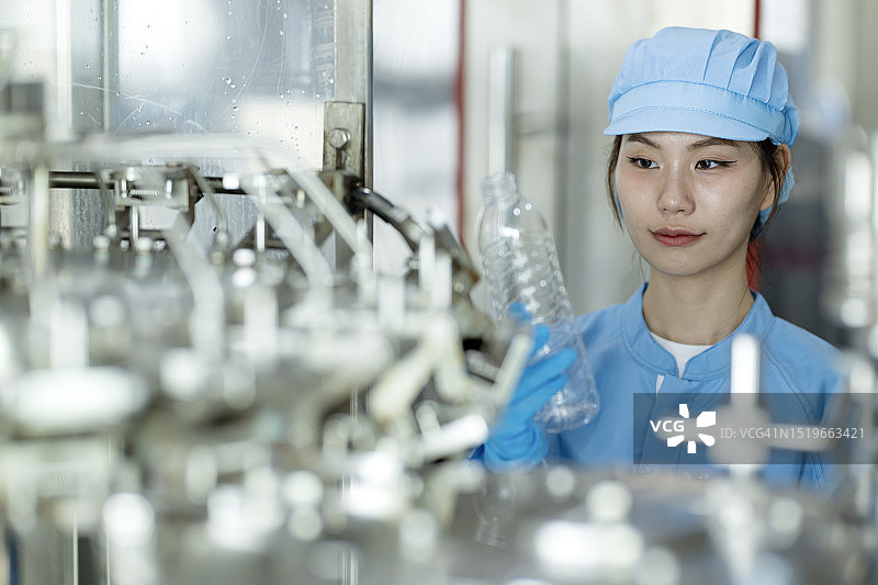 水灌装过程中的质量与安全检查：女工程师在生产线上进行质量控制图片素材