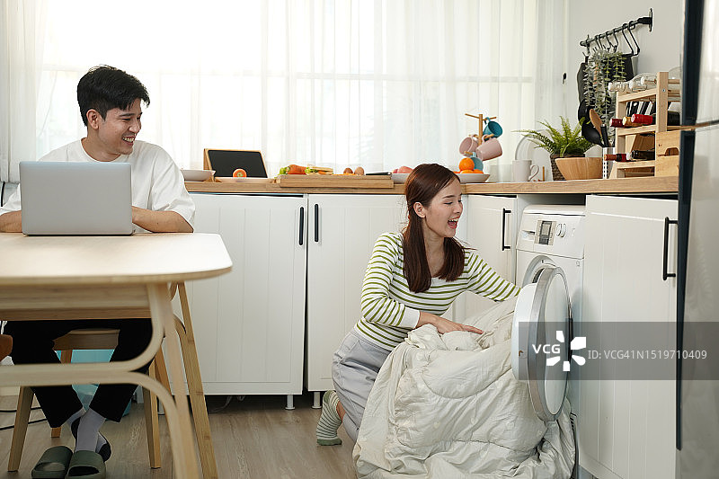 亚洲夫妇正在洗衣机里清洗毯子图片素材