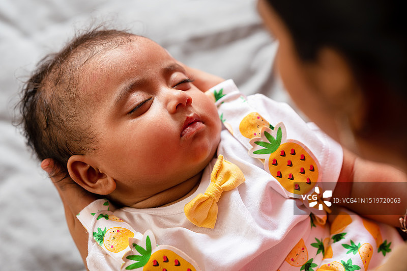 新生女婴在母亲的膝盖上睡觉图片素材