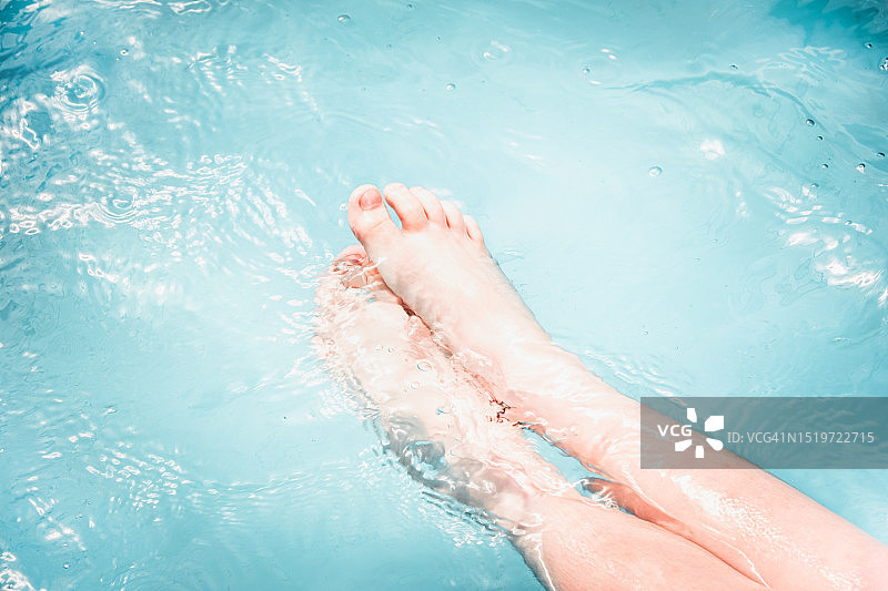 孩子在游泳池的蓝色水下赤脚图片素材