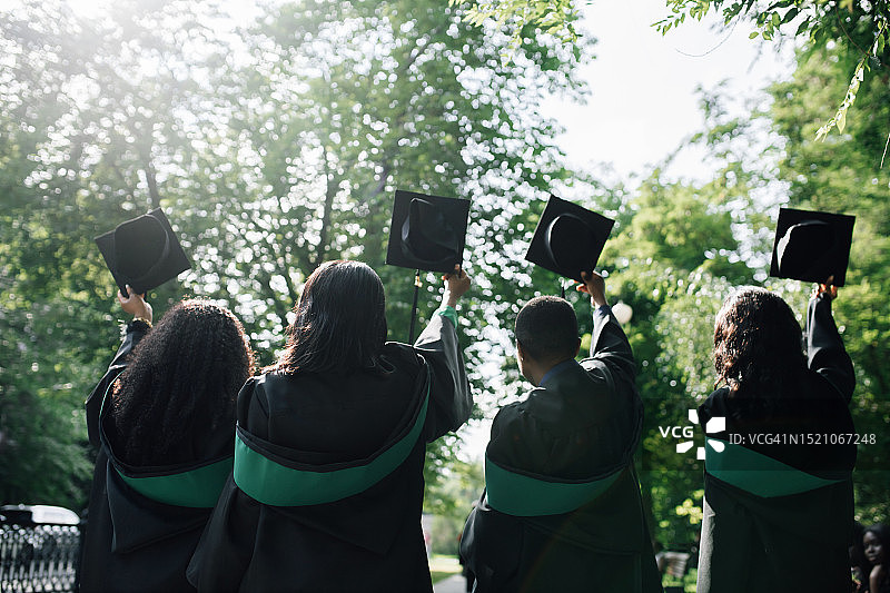 穿着毕业礼服的女学生手拿毕业帽的后视图图片素材