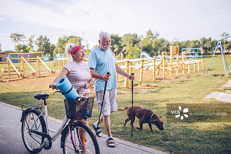 年长的男人在公园骑自行车和散步图片素材