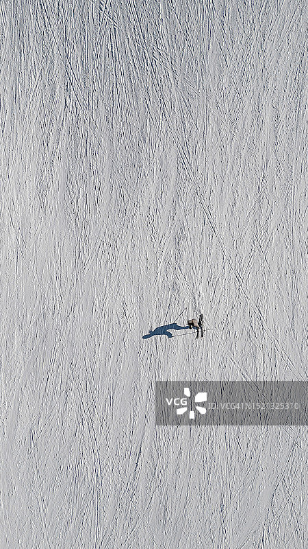 在阳光明媚的冬日，滑雪者在滑雪坡上滑雪的航拍图像，意大利图片素材