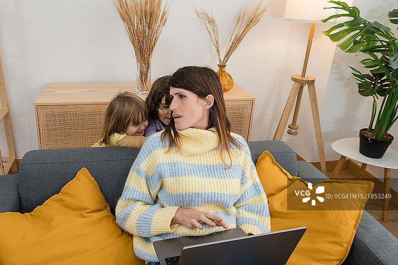 母亲在家工作，孩子们吵闹着要玩耍图片素材