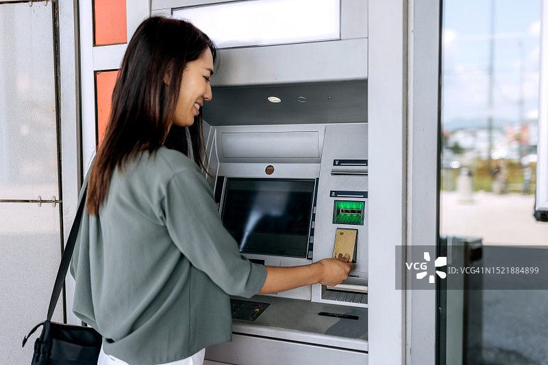 在自动取款机上取款的年轻休闲女子图片素材