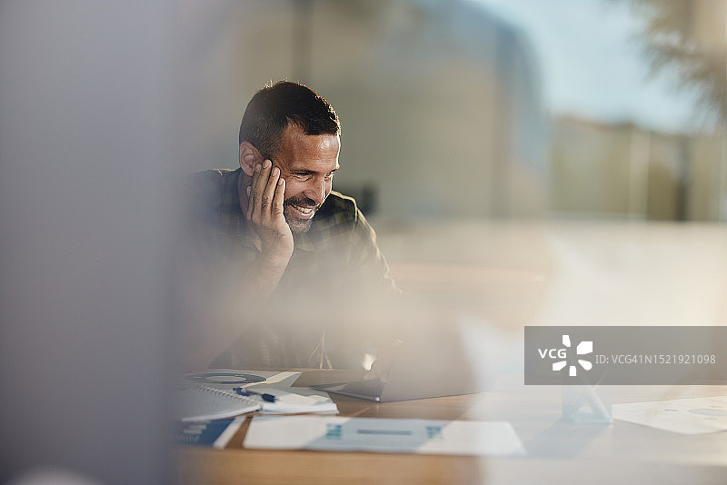 快乐的商人在休闲办公室使用笔记本电脑图片素材