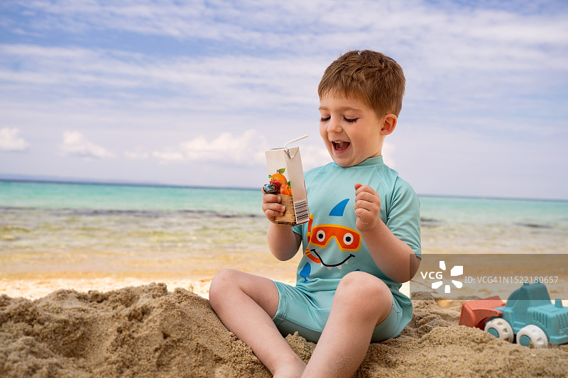 小男孩在海滩上喝果汁图片素材