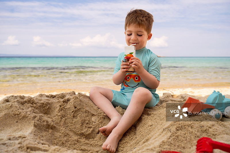 小男孩在海滩上喝果汁图片素材