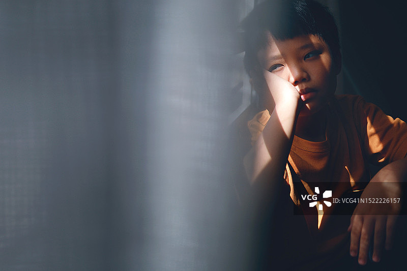 若有所思的儿童看着窗外，表情悲伤孤独图片素材