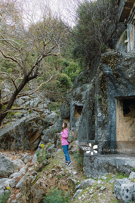 身穿粉色毛衣，背着背包，探索土耳其森林中古城遗址的女人图片素材
