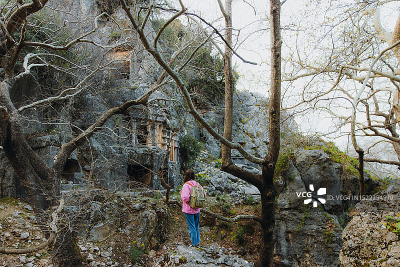 身穿粉色毛衣，背着背包，探索土耳其森林中古城遗址的女人图片素材