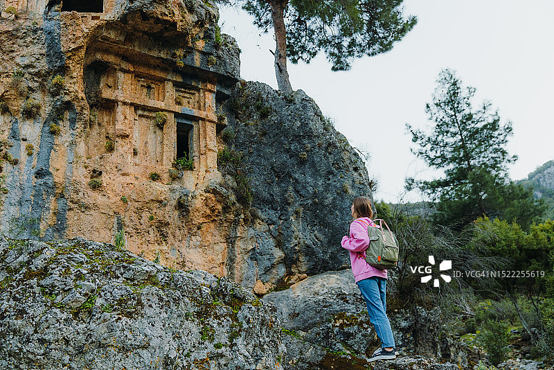 身穿粉色毛衣，背着背包，探索土耳其森林中古城遗址的女人图片素材