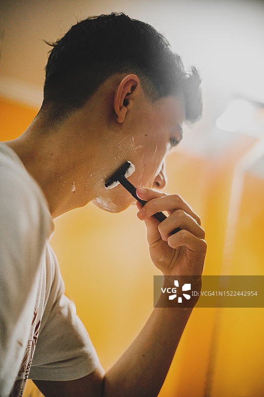 年轻男人使用手动剃须刀图片素材