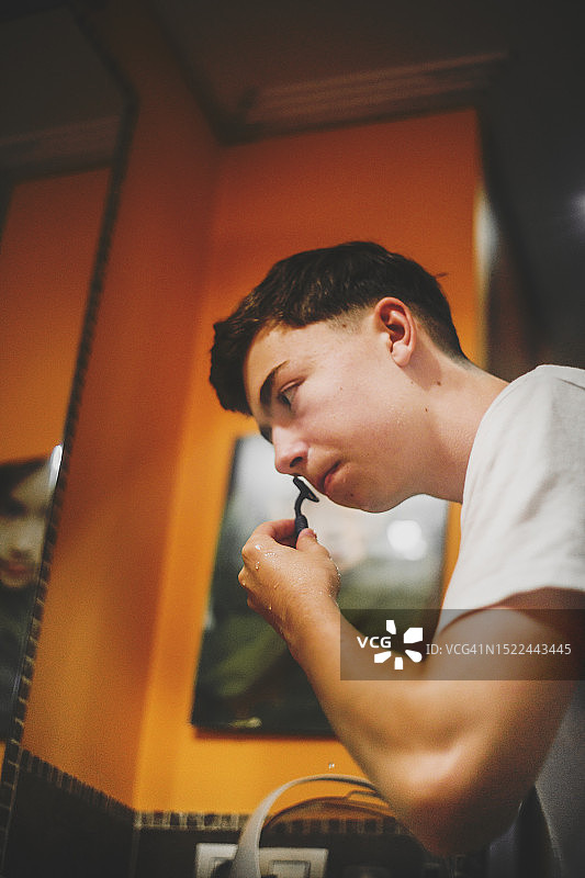 年轻男人使用手动剃须刀图片素材