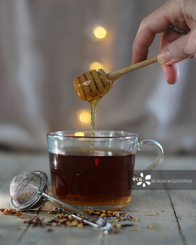 女子往杯子里倒蜂蜜图片素材