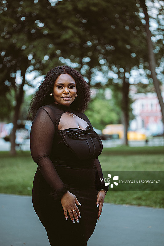 穿着合身黑裙的多民族女人在公园看向镜头图片素材