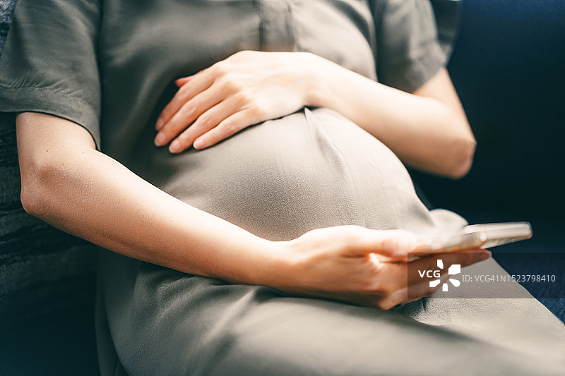 孕妇使用手机上的孕期跟踪应用（未识别面部）图片素材