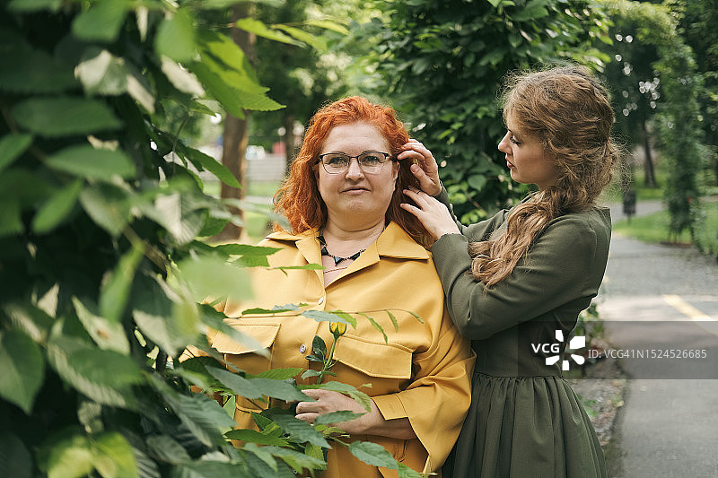 年轻女人在户外整理红发女人的头发图片素材