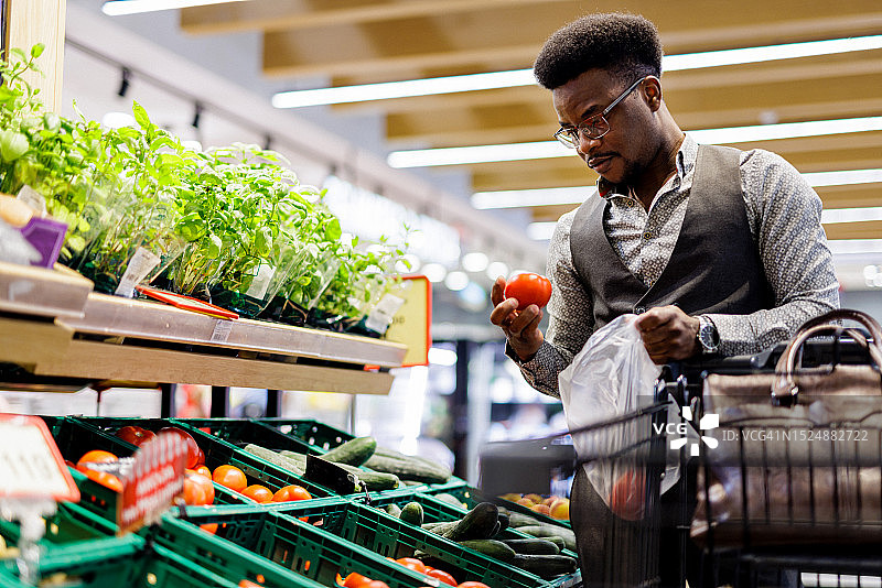 在超市挑选西红柿的年轻商人图片素材