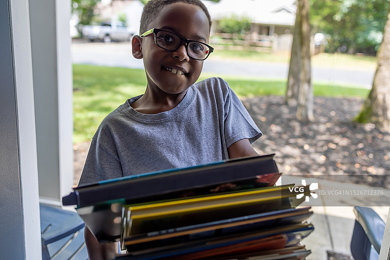 抱着一摞图书馆书籍的年轻黑人男孩图片素材