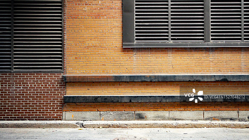 加拿大魁北克省蒙特利尔的棕色砖墙，带有通风格栅和水泥地面图片素材