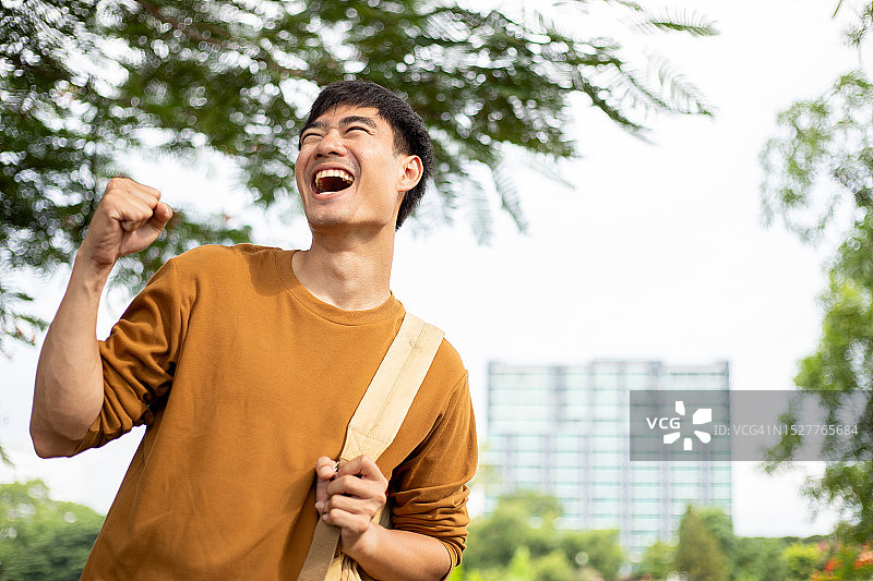 快乐的年轻亚洲男子，休闲装扮，笑容灿烂图片素材