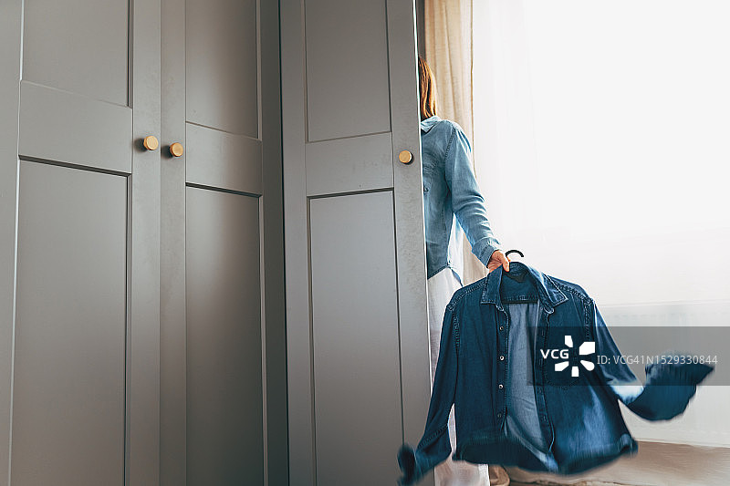 可爱年轻女人站在衣架前挑选衣服图片素材