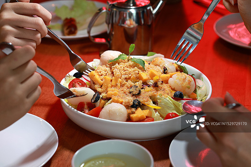 朋友们一起分享享用一碗色彩鲜艳的沙拉特写图片素材