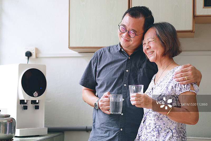 中年儿子搂着年长的母亲在厨房里喝酒图片素材