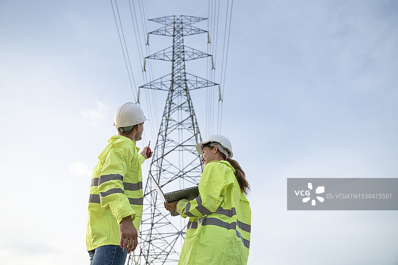 电气工程师在电气塔上工作，讨论电线杆的状况图片素材