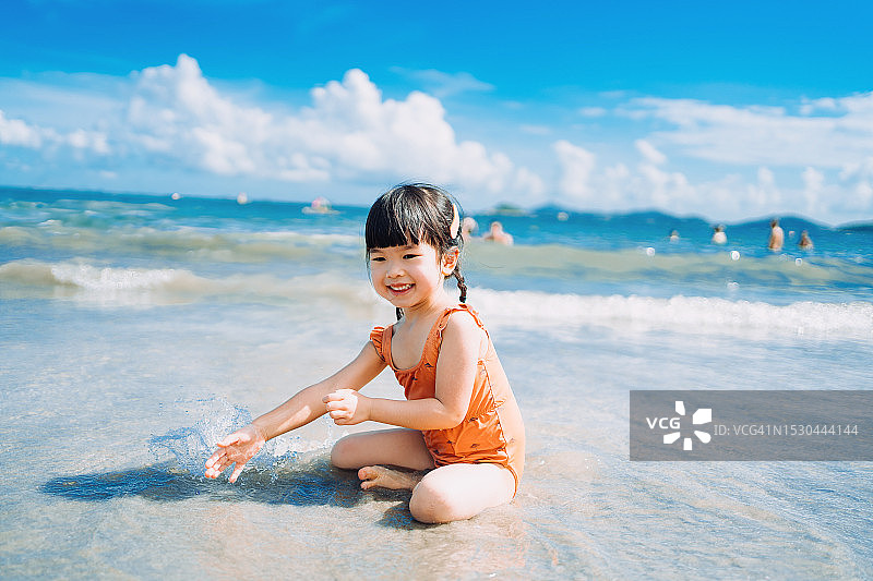 快乐的亚洲小女孩在海边玩水，晴朗夏日图片素材