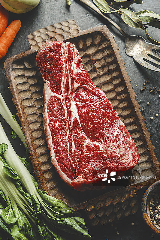 厨房餐桌木盘上的生牛腩和复古餐具图片素材