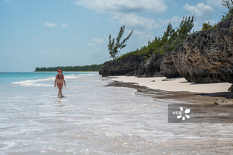 女人在白色海滩的浅水中漫步图片素材