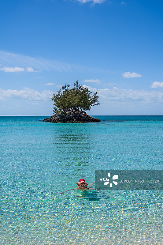 戴着红帽的女人在清澈的海水中放松图片素材