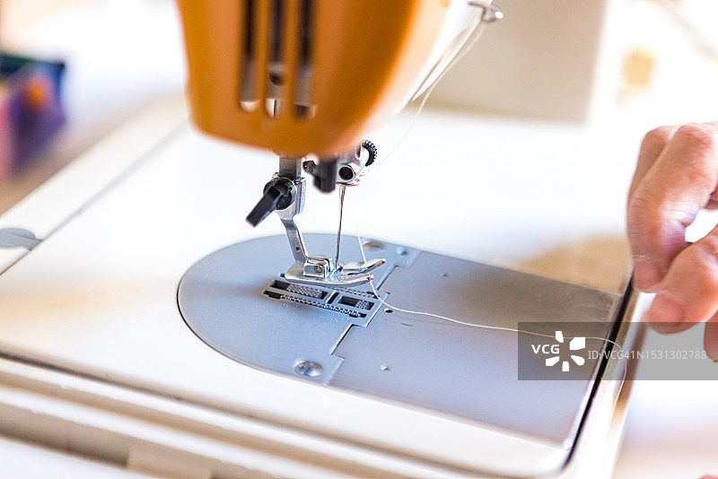 退休裁缝的双手缝纫特写：穿针引线图片素材