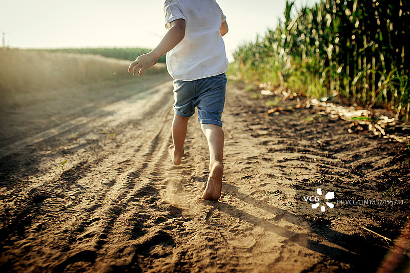 在阳光明媚的夏日日落时分，快乐的小孩在田野里奔跑玩耍图片素材