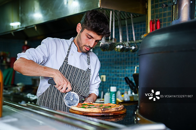 厨师在厨房烤箱旁准备披萨图片素材