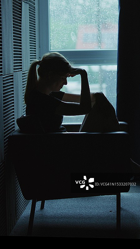 女孩坐在黑暗的房间里，遭受精神崩溃——抑郁症图片素材