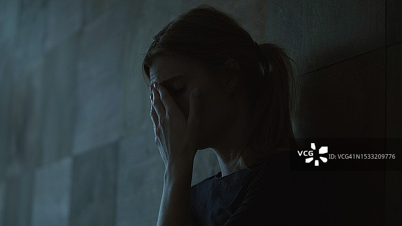 女孩坐在黑暗的房间里，遭受精神崩溃——抑郁症图片素材