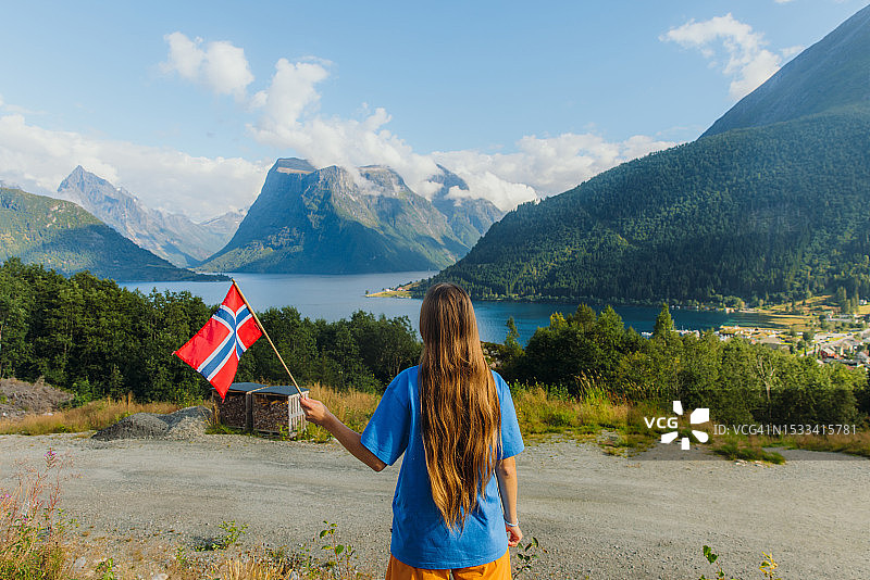 手持挪威国旗，欣赏Sunnmore阿尔卑斯山美景的旅行女人图片素材