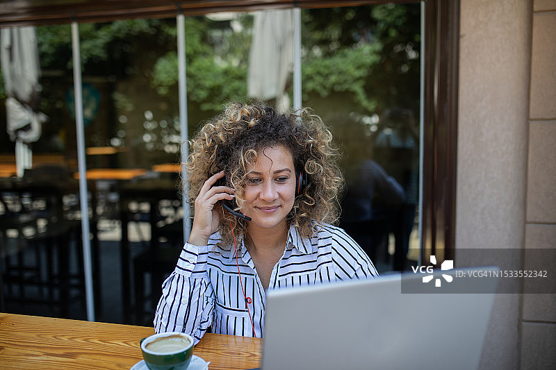 在咖啡馆里用笔记本电脑工作的非裔发型年轻女子图片素材