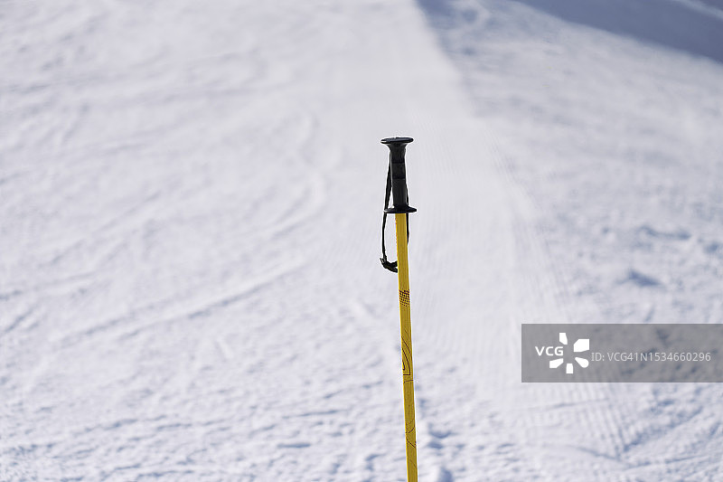 阳光明媚的雪地黄色滑雪杖特写图片素材