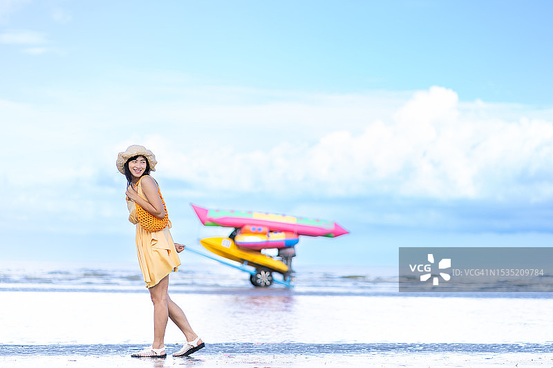 亚洲年轻女子在海边度假，享受椰子树海岸线图片素材