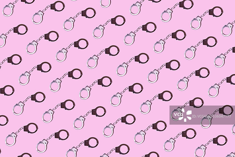 粉色背景上的金属手铐图案，警察、监狱、囚犯、非法、抢劫、法律、审判和小偷概念图片素材