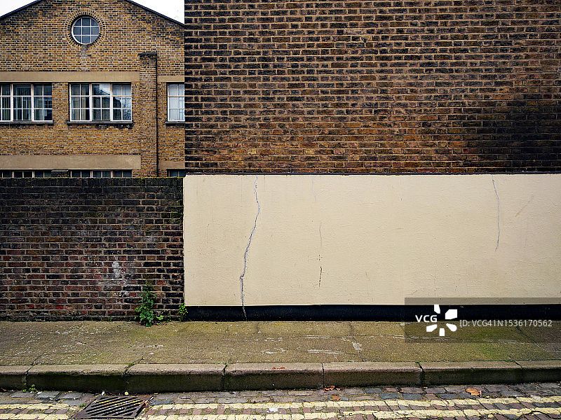 英国伦敦的建筑后立面，风化棕色砖墙和水泥人行道图片素材