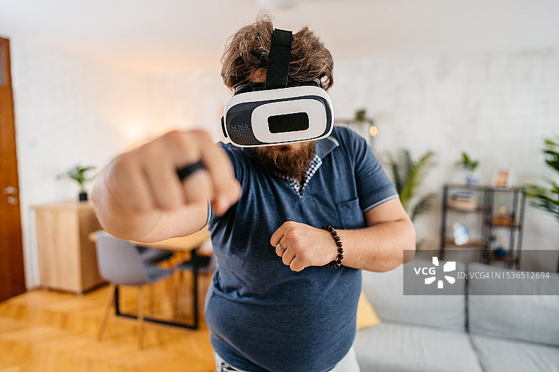 在家戴VR头显玩拳击游戏的年轻男人图片素材