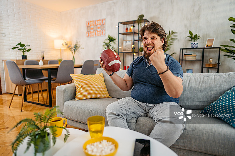 在家看电视橄榄球比赛的年轻人图片素材