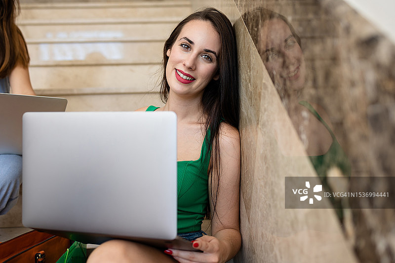 看笔记本电脑对着镜头微笑的女性图片素材